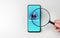 Hand with Magnifying glass on cell phone, an alarm sign detecting malware. Mobile phone security concept. Virus alert. Search for