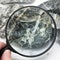 Hand with magnifying glass examines asbestos fibers