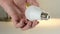 Hand of male holding a white glass light bulb .