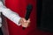the hand of a male journalist holds a microphone on a red background