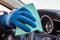 Hand of man in blue protective glove is wiping Steering Wheel with a cloth. Disinfection during coronavirus or Covid-19 protection