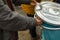 A hand of a man in a grey jacket throwing out trash into a silver and blue trashcan