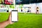 the hand of man hold mobile phone over blurred athlete are playing footbal or Soccerl on artificial yard