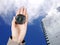 The hand of a man holding a magnetic compass over a city buildings