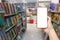 Hand of a man holding smartphone device in the Bookstore background