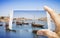 Hand of man holding a smartphone with a picture of a typical portuguese boats used in the past to transport the famous port wine