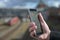 Hand of a man with a mobile phone, station, railroad tracks and train blurred in the background, concept for tracking and ticket