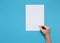 Hand Of Man With Pen And Blank Sheet Of Paper On A Blue Background, Top View. Office Space Creativity Minimalism Concept