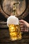 Hand of man is pouring a large lager beer in tap from wooden beer barrel