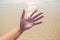 A Hand of a man reaching to towards beach. Hand make symbol