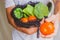 Hand of a Man showing a tomato and holding a cotton mesh bag reusable full of eco vegetables on the background. Eco friendly