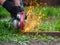 Hand of man with steel cutter tool on green background. Worker outside, cut the metal rails. Process with angle grinder