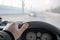 Hand of a man on the steering wheel of a car that is driving on a slippery road