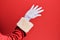 Hand of a man wearing santa claus costume and gloves over red background presenting with open palm, reaching for support and help,