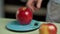 Hand of a man weighs several red apples on a kitchen scale, close-up