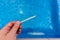 Hand with measuring pool strips to check water quality in a swimming pool - pool maintenanc