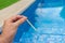 Hand with measuring pool strips to check water quality in a swimming pool - pool maintenance
