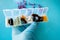 A hand with a medical glove holds multi-colored capsules, a pill box with medicines on a blue background .