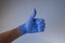 Hand in medical glove thumb up on blue background-  Covid-19