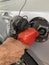 Hand of a men with a hose of fuel refueling a vehicle