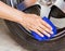 Hand with microfiber cloth cleaning wheel car