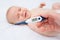 the hand of a mother or doctor holding a thermometer with a mark of 39.3 degrees on the background of a crying baby.