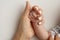 The hand of a mother and father close-up holds the fist of a newborn baby.