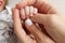 The hand of a mother and father close-up holds the fist of a newborn baby.