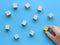 Hand moves a wooden cube to the group of cubes on blue background.