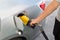 Hand with nozzle fueling unleaded gasoline into car