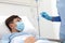 Hand nurse with thermometer measures fever on patient child in hospital bed, wearing protective surgical mask, corona virus covid