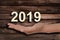 Hand offering 2019 numbers, wood background