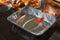 Hand oiling a baking dish with an orange brush