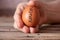 The hand of an old woman holds in her hand a chicken egg with the text 2022 on a wooden table in the kitchen, a chicken egg