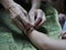 Hand of old woman waving a white string  Sai Sin  around her granddaughter hands - Thai traditional blessing from an elder one