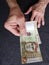 hand of an older man holding peruvian banknote