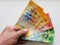 hand of an older man holding swiss banknotes of different denominations