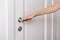 Hand opens the door metal handle. Woman hand using towel for cleaning home room door link. Sanitize surfaces prevention