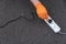 A hand in an orange glove inserts a power cord into a white extension cord on a gray background