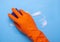 hand in orange rubber glove washing blue surface with sponge with soap foam