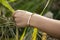 Hand outdoor touching plants with pearl and hematite bracelet