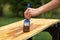 Hand with paintbrush painting a wooden board in garden.