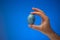 Hand painted and decorated blue easter egg held in hand by Caucasian male. Close up studio shot, isolated on blue background