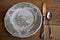Hand-painted porcelain plate with cutlery wooden background