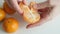 Hand peeling a mandarin orange on white background. Close up.