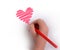A hand with a pencil draws a heart in red.copyspace for text