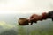 Hand of person holding traditional wooden cup of tea or coffee in hand on mountain misty morning view background