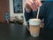 Hand of a person mixing morning coffee mocha on table. Photo behind the bar counter with blurred background and soft