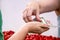 Hand of person receiving American dollars from another person with blurred cherry tomatoes below against white background