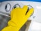 hand of a person with yellow gloves starting a white semi automatic washing machine